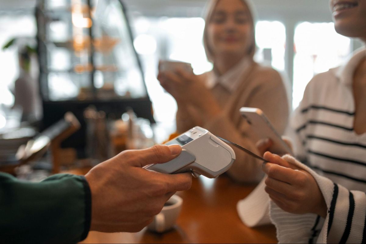 Pessoa pagando por aproximação de cartão (NFC) em café.