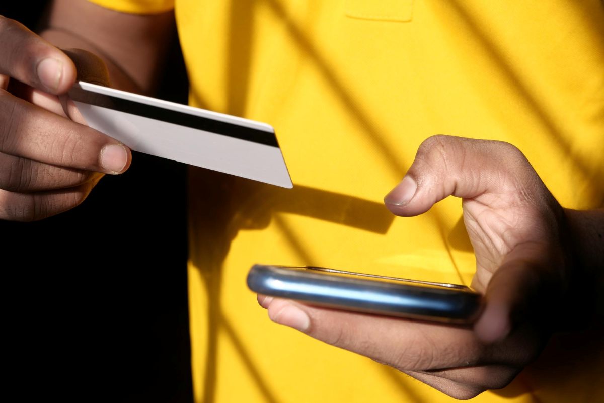 Pessoa efetua pagamento por aproximação com cartão em celular.