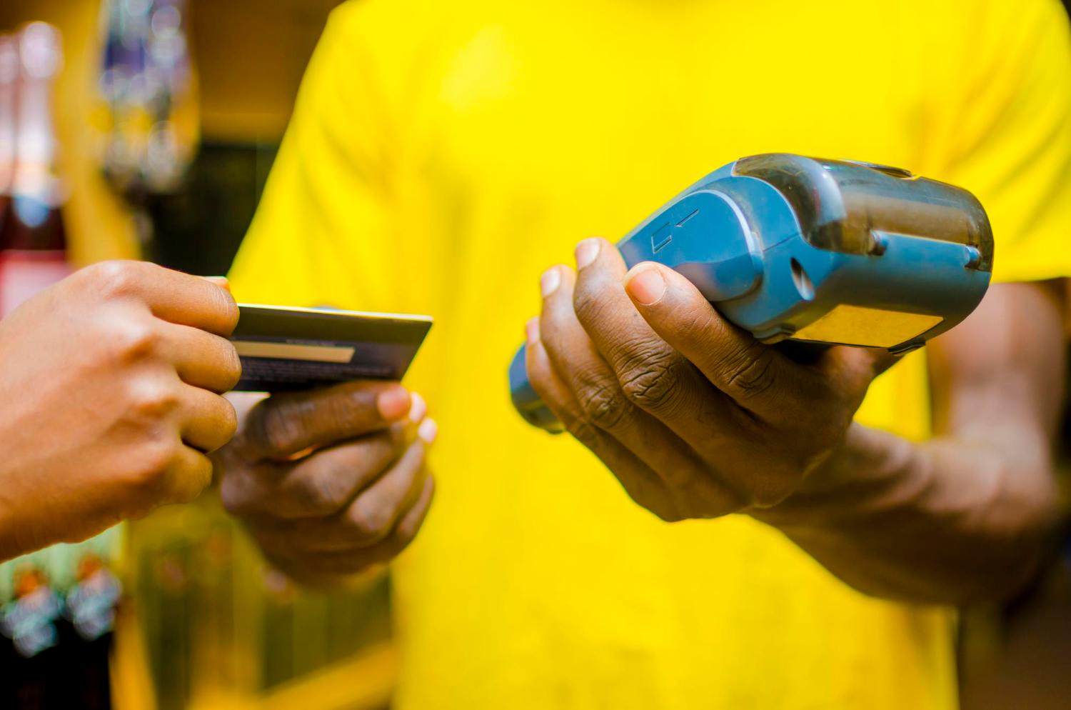 Pessoa segura maquininha de cartão enquanto recebe cartão de crédito.