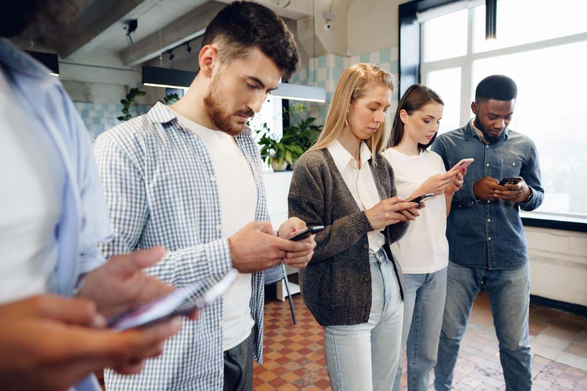 Membros de equipe consultam seus celulares.