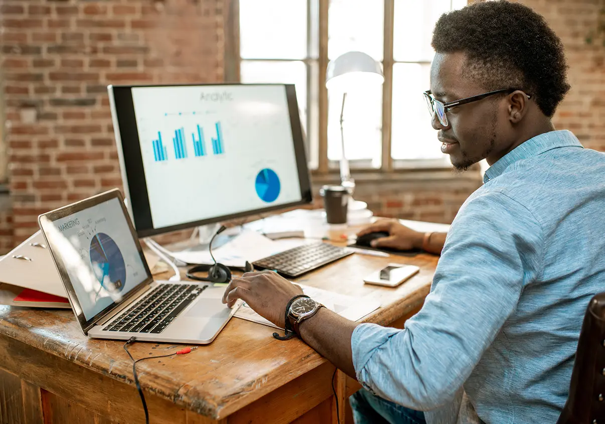Homem analisando relatórios com gráficos nos computadores