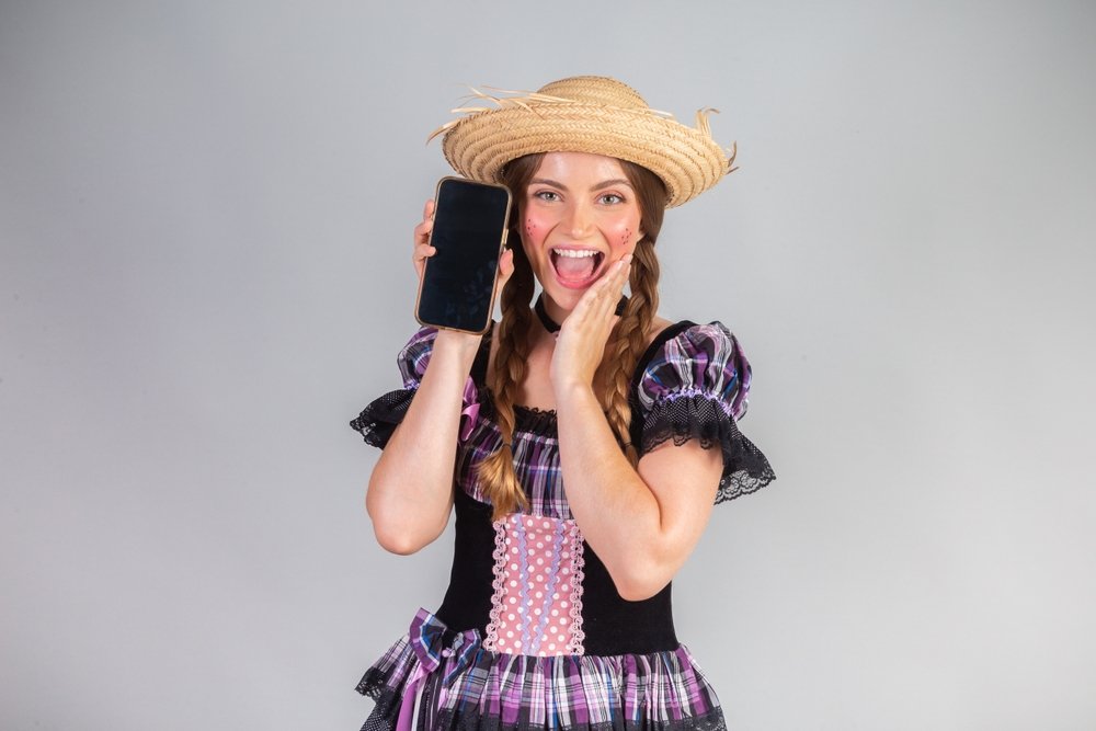 Empreendedora com celular pronto para receber pagamentos por aproximação na festa junina.