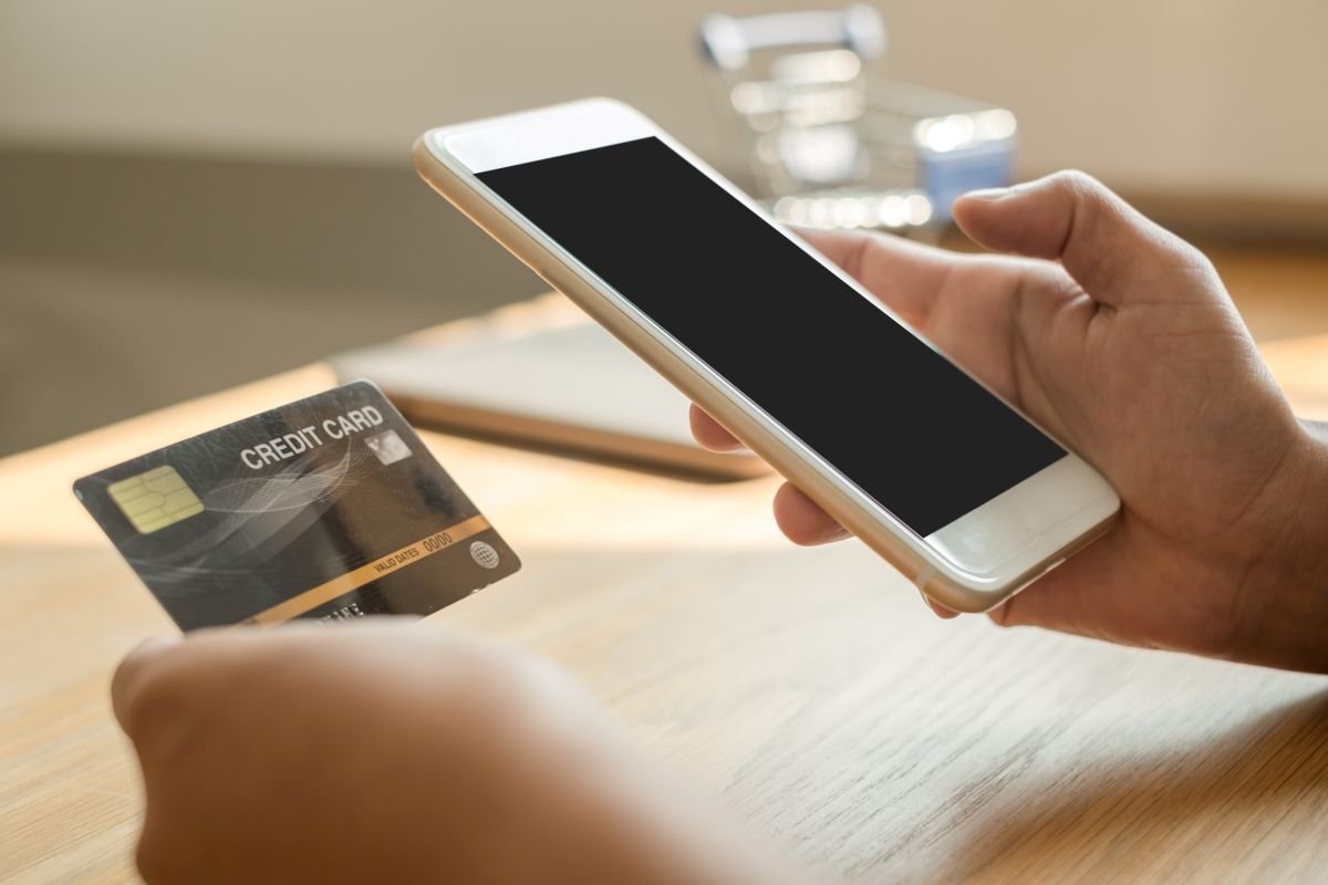 Vendedora usando iPhone para receber pagamento por aproximação de cliente em loja física.